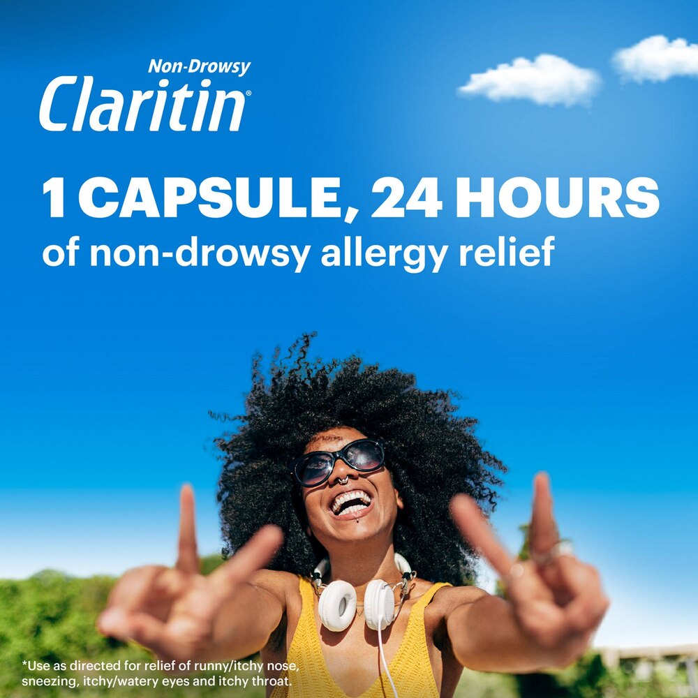 Woman with sunglasses and headphones against a blue sky, promoting Claritin allergy relief.