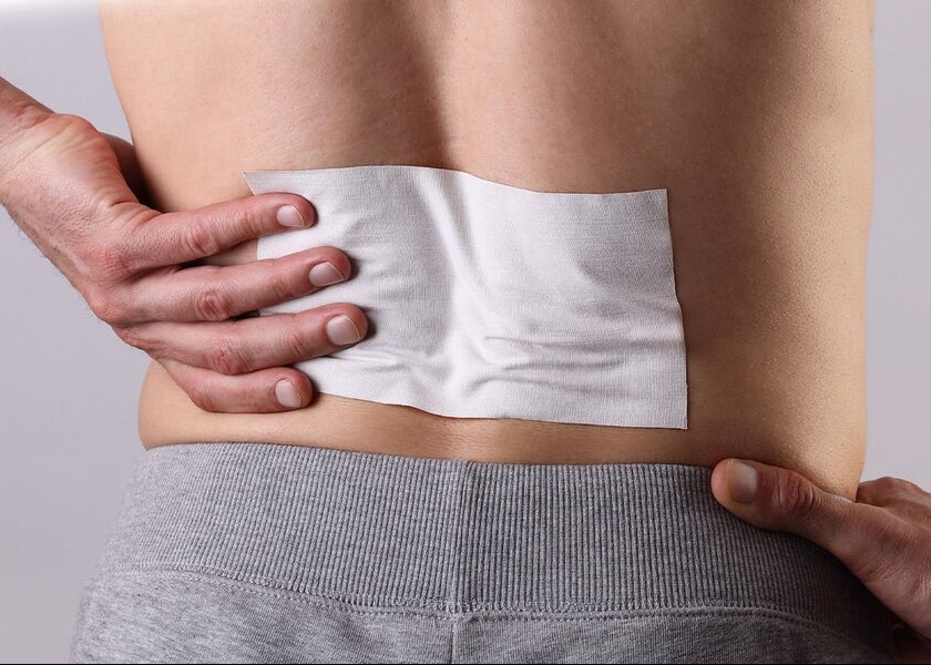 Person applying a white patch to their lower back with text 'Easy-to-Apply Targeted Pain Relief' on a yellow background.